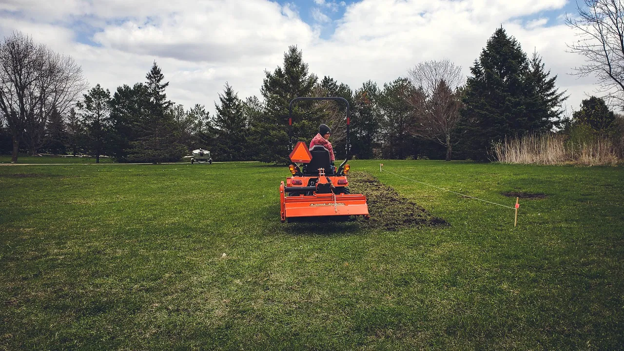 Ashley Headrick on a Kubota Tractor tilling a lawn into a new garden